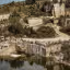 The image displays a well-composed view of a quarry with a reflective body of water in the foreground and buildings nestled on a hill in the background. The key elements are in focus, contributing to its photo-realistic quality.