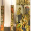 A photograph showcasing several historical panel paintings, likely religious art, displayed in a museum or gallery setting. The image features two vertical columns of smaller, individual painted panels on the left, and a larger, multi-figure panel painting on the right, which is partially cropped.