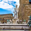 A well-composed and vibrant photograph of the Fountain of Neptune in Florence, Italy, showcasing the intricate details of the sculptures and the surrounding historic architecture under a bright, clear sky.