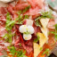 An overhead shot of a well-arranged charcuterie board featuring a variety of cured meats, cheeses, and fresh arugula.