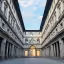 A well-composed editorial image of a grand, symmetrical architectural courtyard, possibly the Uffizi Gallery, featuring classical buildings with numerous windows and columns under a bright sky.