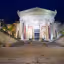 A well-composed and sharp image of a grand classical building at night. The artificial lighting effectively illuminates the structure, highlighting its architectural details. The deep blue night sky provides a good contrast.
