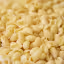 A close-up shot of uncooked, dry pasta, appearing to be a mix of garganelli and cavatelli shapes, scattered across a surface. The foreground elements are in sharp focus, while the background is softly blurred, emphasizing the texture and form of the individual pasta pieces.